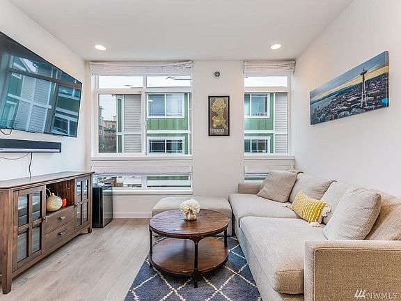 Relax and enjoy in the bright living room. The large windows let in lots of natural light year round and come with custom blinds on both the top and bottom windows.