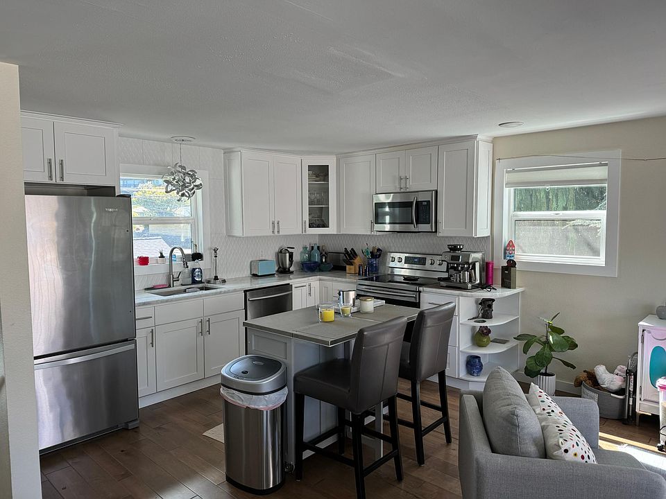 Newly renovated kitchen with natural stone countertops and stainless steel appliances including a dishwasher.