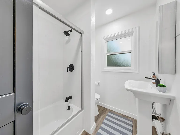 Bathroom with full tub and glass shower enclosure.