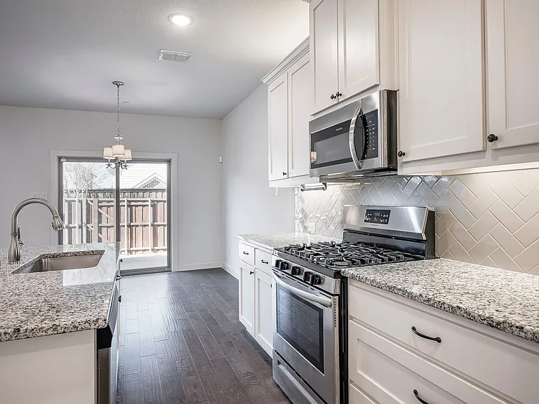 Beautiful neutral paint colors and backsplash add elegance to this kitchen.