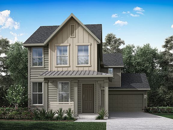 A two-story, gable-roofed house with a porch and a garage, surrounded by lush greenery and a clear b