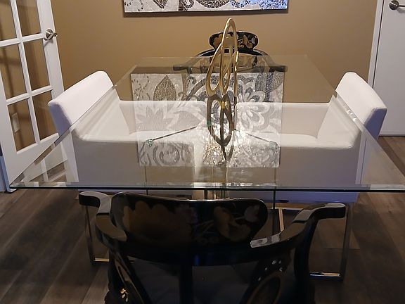 Restoration hardware white new chair with oriental handmade chairs with a glass table top alongside handmade wall glass hanging.