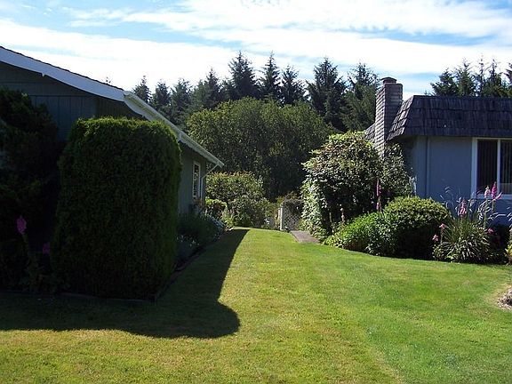 Access to back yard from the right side with lots of plants and flowers.