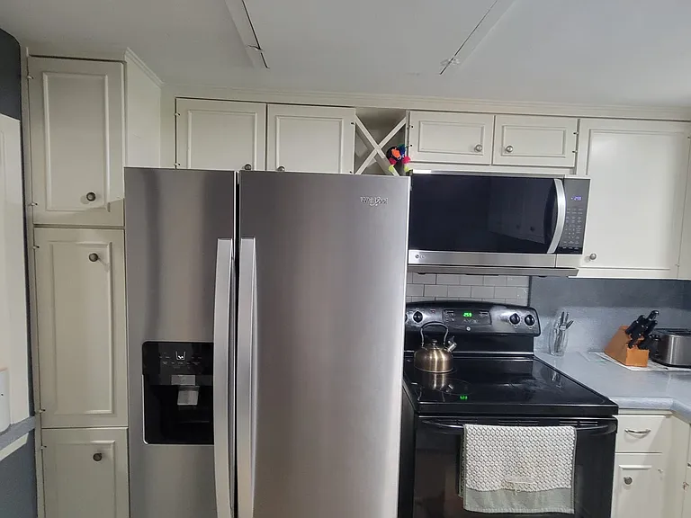 Kitchen appliances with utensils and kitchen plates and bowls. Wine rack.
New refrigerator.