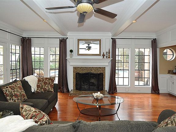 The family room features wood flooring, a fireplace with a granite surround and white wood mantel, and windows looking out to the pool and backyard.