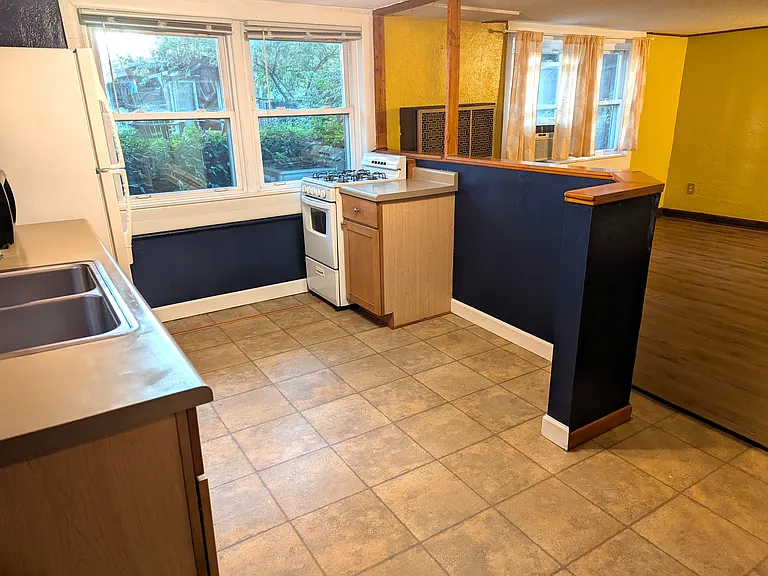 Kitchen opens to living room. Four windows look out to backyard.