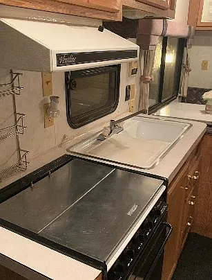 Compact kitchen workspace with double sink, upper wood cabinetry, and a built-in microwave for everyday cooking needs.