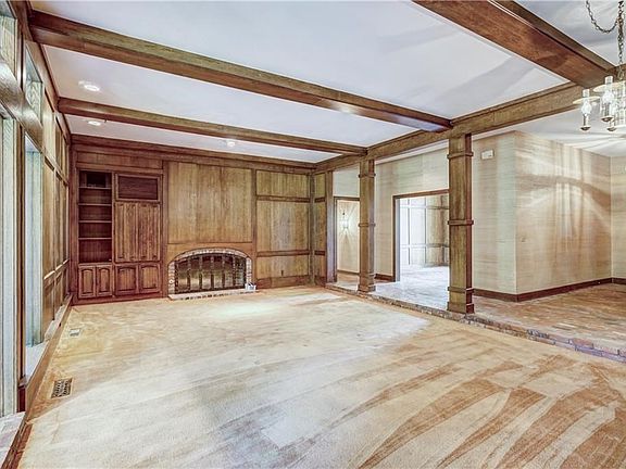The homes primary living space has stunning wood work, a wet bar, fireplace, built-ins and beams.  The entry  is on the right and you can see the formal dining room entry between the two solid wood posts.