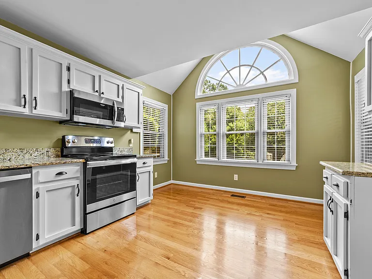 Kitchen features granite countertops, white cabinetry, stainless steel appliances, and hardwood floors.