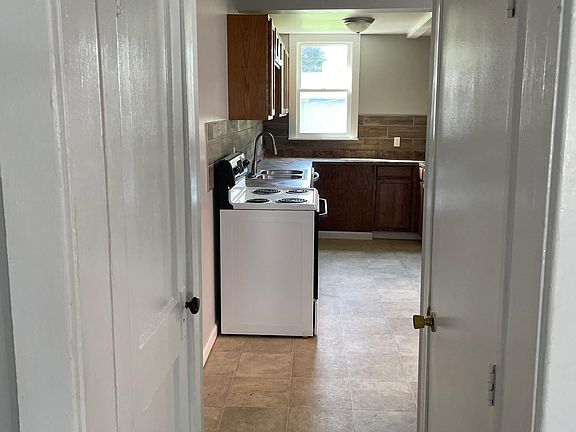 small hall between living room and kitchen. door on left is a coat closet door on right leads to the basement