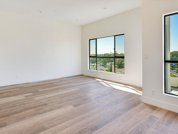 Empty west facing loft styled living/dining/kitchen with balcony