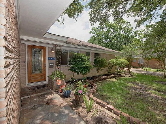 A slate walkway and porch bordered by landscaping lead to the beautiful front door.