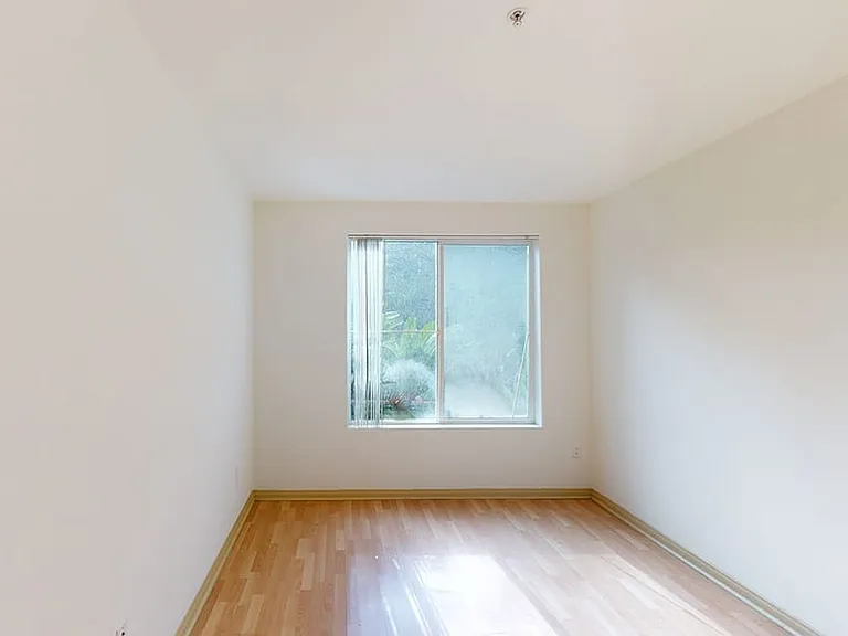 Spacious apartment bedroom with wood-style flooring.