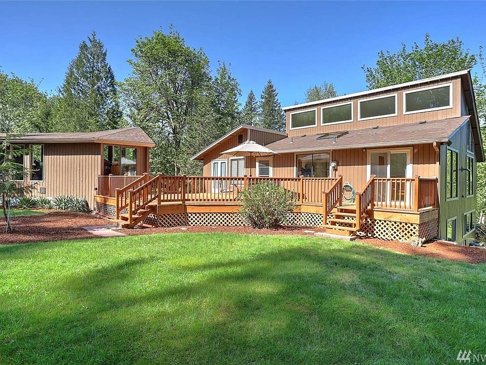 This Northwest Contemporary home sits on a shy 5 acre parcel that is wooded, private and serene. It offers a long private winding driveway and the home sits to the rear of the property. It is wooded and boasts a pond that has been a home to a family of beavers. The pond is currently overgrown but could be cleared to further enjoy it. The garages will hold 4 or more cars and there are several work benches and lots of shelving. This structure we measured around 2000 square feet and the upper level could be a great spot for an artist studio. There is also a two-car tandem covered carport area behind the garage and there is lots of unfinished square footage in the lower and upper section of the garage that has all of the windows. Both of the garage doors and the man door have been replaced on the garage. The roof of the garage is 1 year old and the roof of the house was completed in the Summer of 2014.