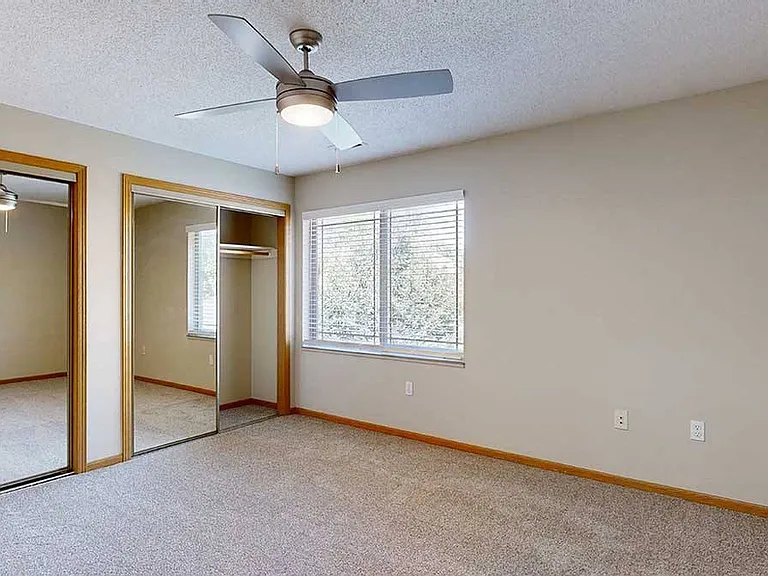 The Findad bedroom features large windows, mirrored closets, and a ceiling fan for added comfort.
