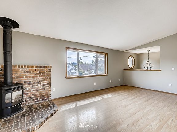 Open living room has a large window overlooking the neighborhood - gas fireplace on the left. The entry light fixture is seen in rear of photo