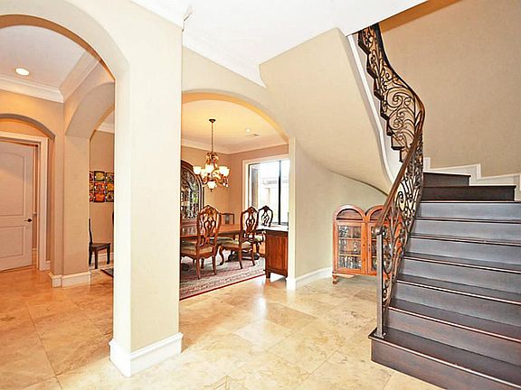 Elegant Two Story Foyer with beadboard ceiling and beautifully scrolled wrought iron curved staircase and rich stained wood