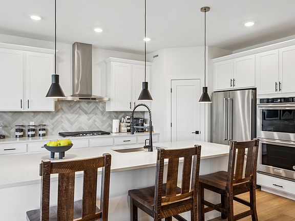 The beautiful kitchen has beautiful white wood cabinetry with black hardware.