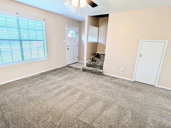 Living area has new carpet, new ceiling fan, and a large window.