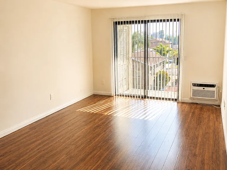 Bright and spacious living area featuring beautiful wood-style flooring, abundant natural light, and direct access to a private balcony.