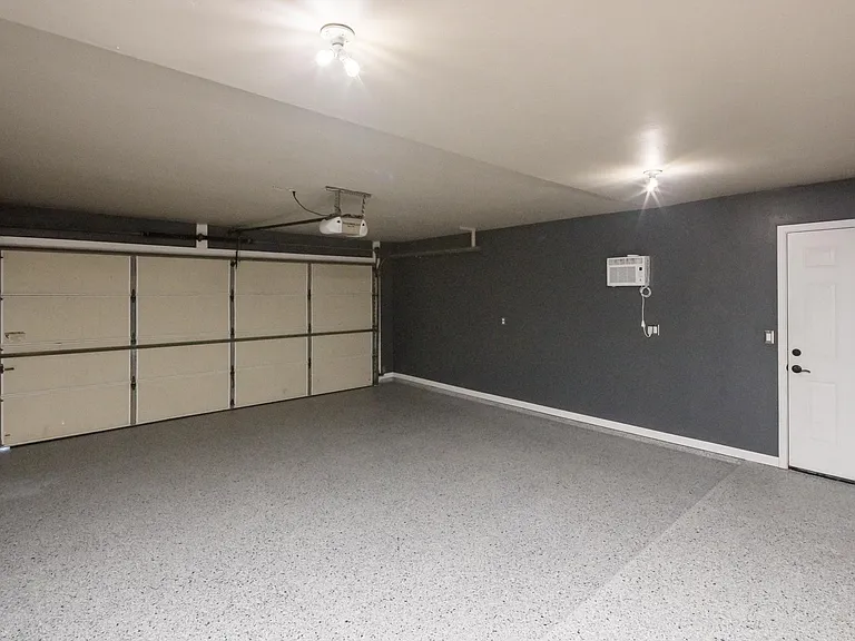 Spacious garage layout showcasing finished walls, clean flooring, and additional storage potential.