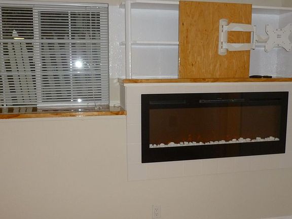 Recessed electric fireplace heater with custom tv mount abov