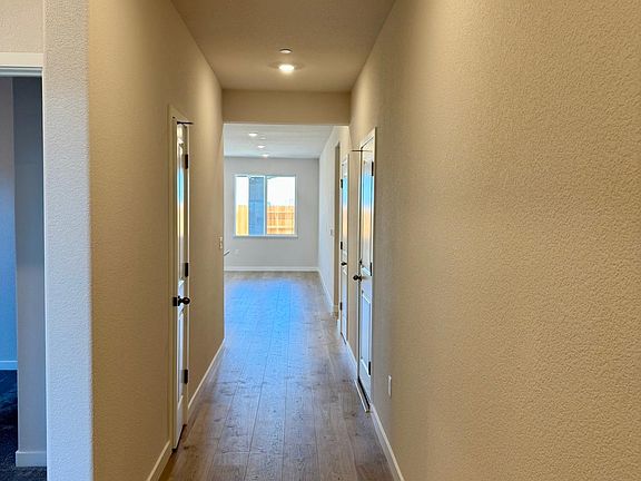 Hallway leading to 2 bedrooms on the left and entering Great room and additional bedrooms