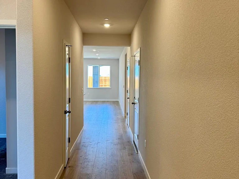 Hallway leading to 2 bedrooms on the left and entering Great room and additional bedrooms