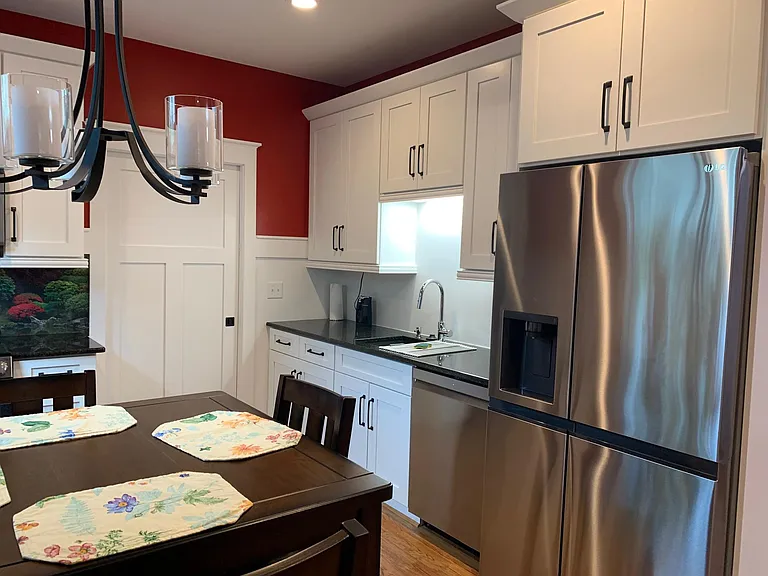 Kitchen with ice maker refrigerator, under cabinet lighting, dishwasher, tons of storage, granite countertops, and counter height table with four chairs.