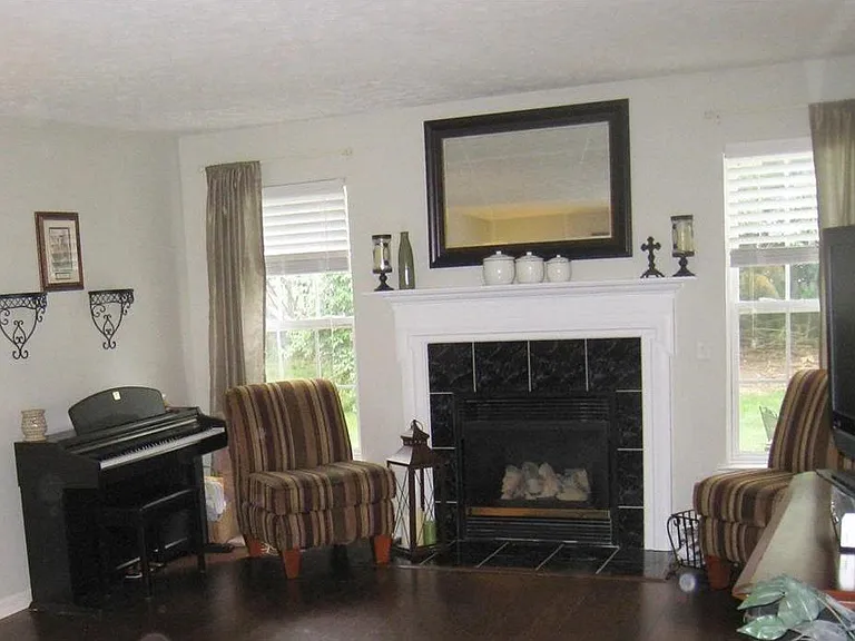 Closer shot of living room back wall with large windows and gas fire place.