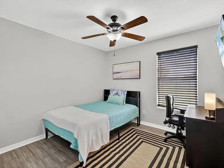 Bedroom 2 featuring a full-size bed, desk, wall-mounted television and full-size closet