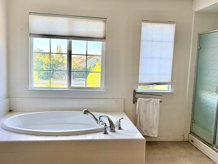 Primary bathroom with a soaking tub, separate shower, and lake views