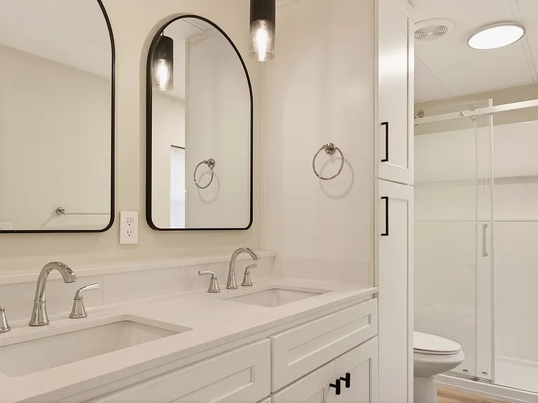 Primary Bathroom with Double Vanity, Quartz Countertops, Arched Mirrors, and Walk-In Shower