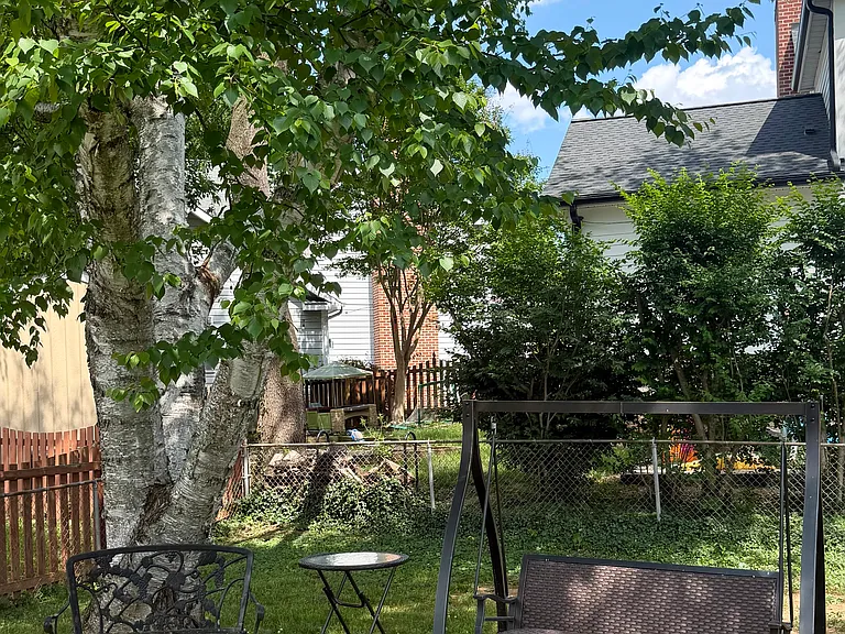 Shaded backyard with swing and sitting area.