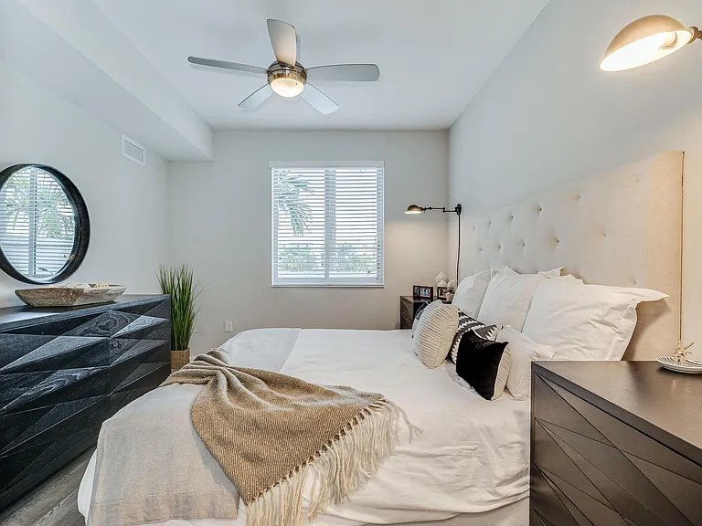 Bedroom Includes Black Dresser, Round Mirror, and Ceiling Fan