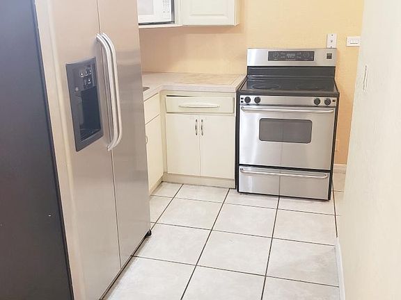 Separate eat-in kitchen with stainless steel appliances, a microwave and ceiling fan.