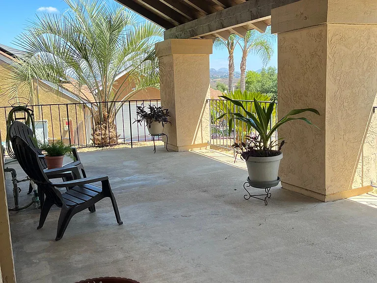 Large private covered front patio enclosed with wrought iron fencing