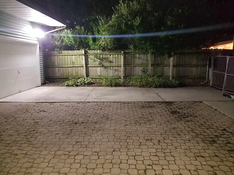 Large paver patio. There is a grass lawn behind garage building.