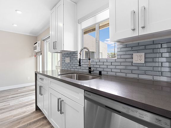 Blue tiled kitchen with stainless steel oven, fridge, dish washer, and fixtures.