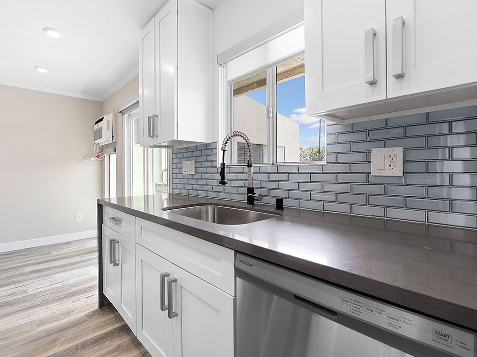 Blue tiled kitchen with stainless steel oven, fridge, dish washer, and fixtures.