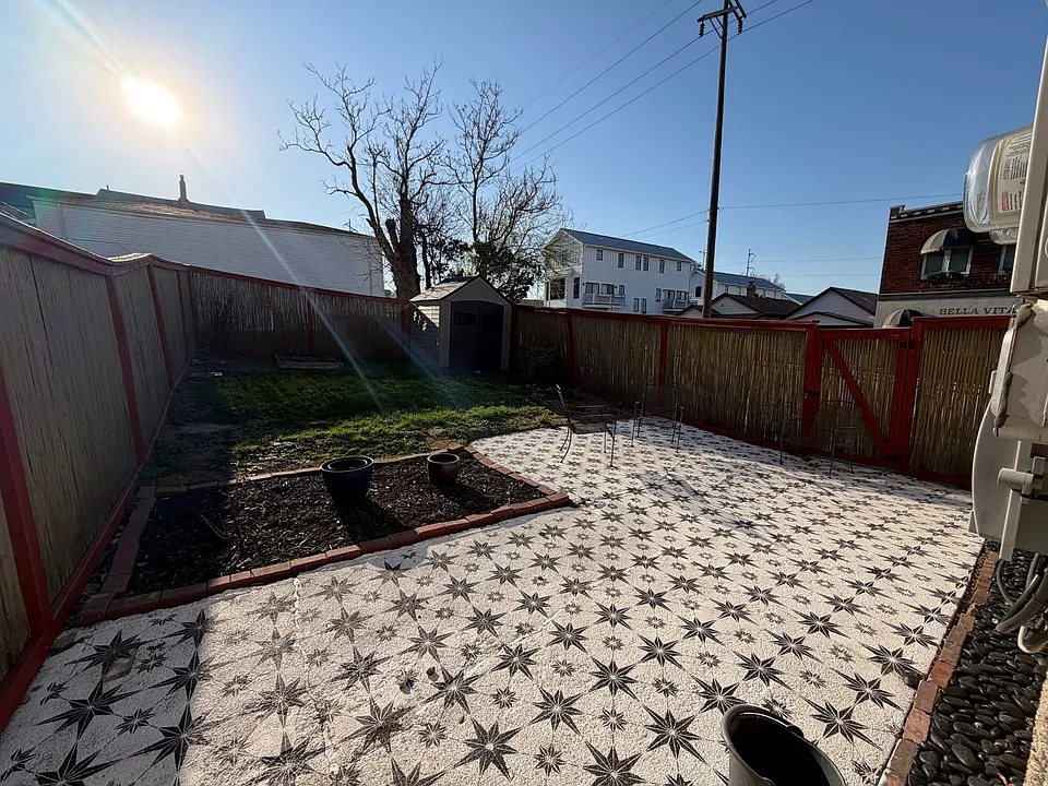 hand stenciled Esty back patio, bamboo fenced in-yard, storage shed, one square garden box, rose bushes and lilac bushes in backyard