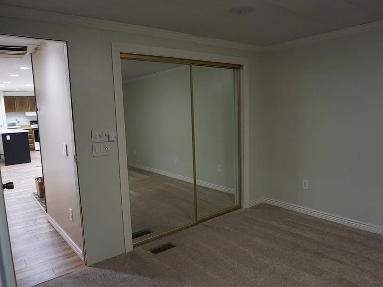 Large walk-in closet in master bedroom with full-length mirror doors.
