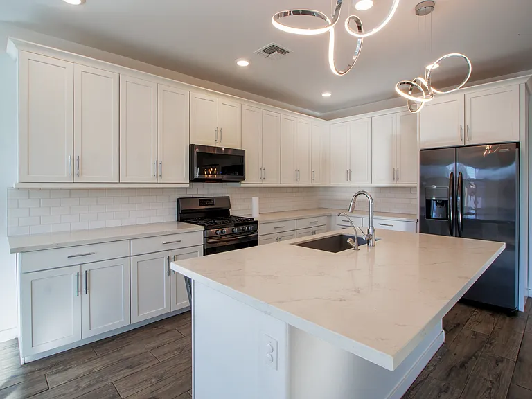 White cabinets with black stainless steel appliances and white granite countertops