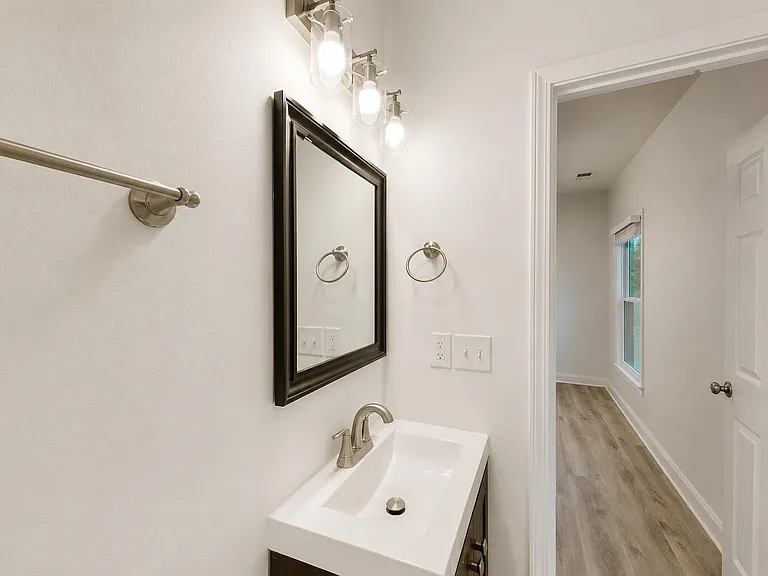 Half bath with sleek vanity, framed mirror, and updated lightingconveniently located just off the hallway.
