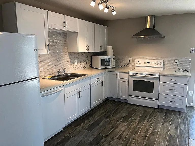 Kitchen with electric stove , garbage disposal, dishwasher and countertop microwave.