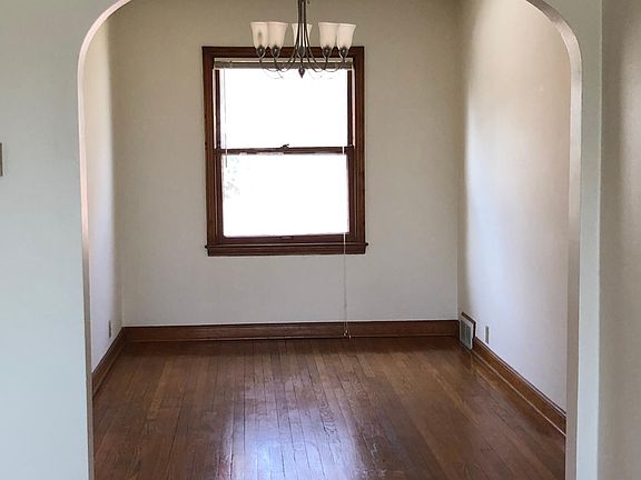 Dining room with hardwood floor leads to kitchen and living room.