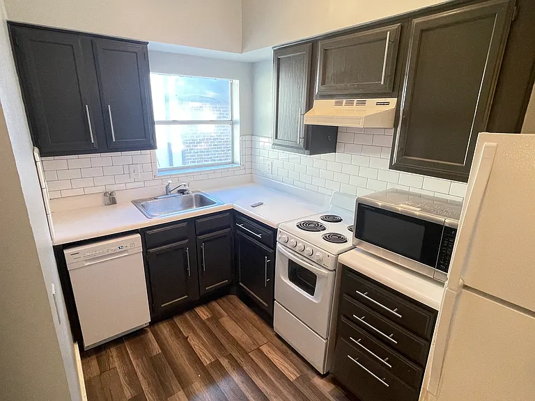 Updated kitchen featuring subway tile backsplash, Euro-style electric range, updated dishwasher, microwave and fridge.