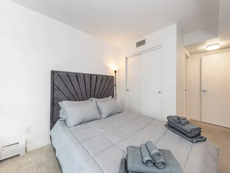 A comfortable queen-sized bed with soft blankets and pillows, perfect for a restful night's sleep. It also includes a large closet for ample storage space.