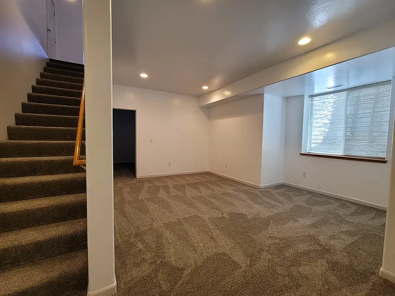 Family room at the bottom of the stairs looking to the back bedroom