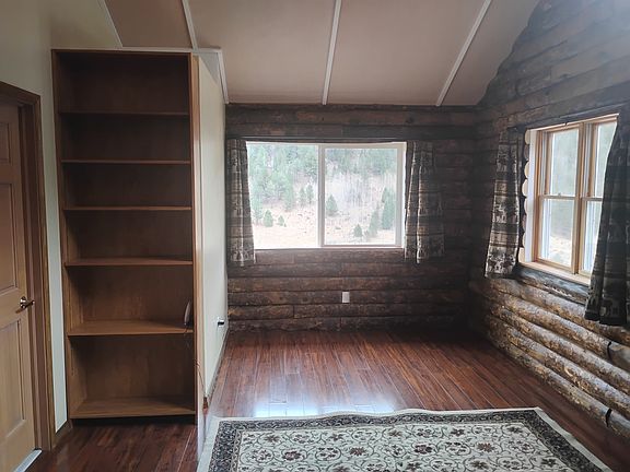 Living room with bookcase. There are three large windows in the living room.